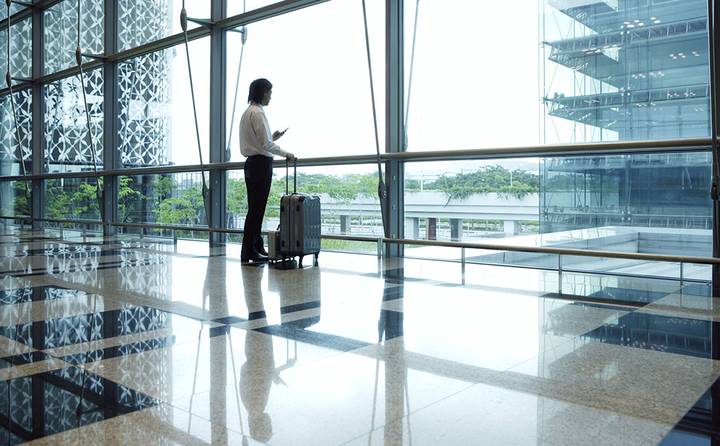 Singapore --- Businessman standing in airport using PDA --- Image by Â© Ocean/Corbis