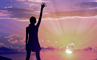 Woman reaching up gazing at brilliant sunset